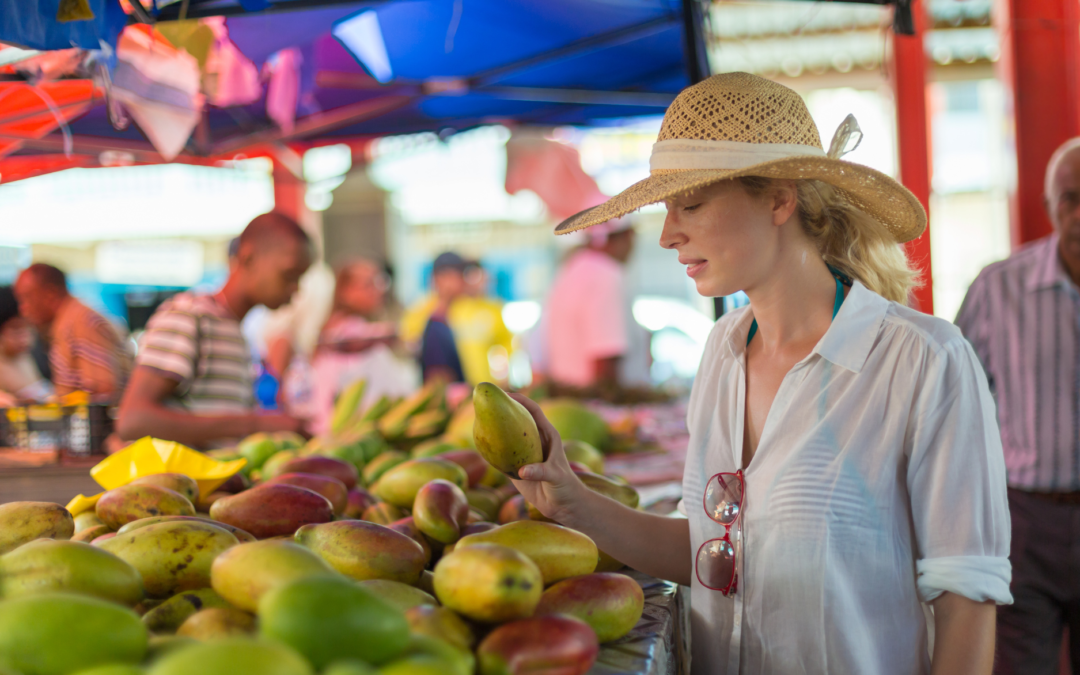 Traveler choosing fresh mangoes at a bustling market, emphasizing local and healthy eating during travel.